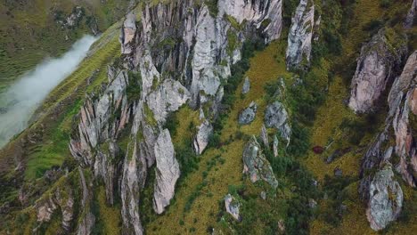 Aerial,-drone-shot-tilting-over-rock-formations,-in-the-Andes-mountains,-on-a-foggy-day,-near-Cusco,-in-Peru,-South-America