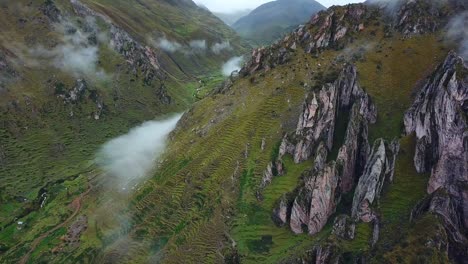 Aerial,-pan,-drone-shot-towards-rock-formations-and-low-clouds,-on-Andes-mountains,-on-a-overcast-day,-near-Cuzco,-in-Peru,-South-America