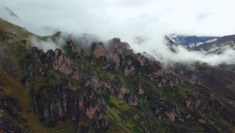 Aerial,-pan,-drone-shot-overlooking-rocky-formations,-low-clouds-and-fog,-in-the-Andes-mountains,-on-a-cloudy-day,-near-Cuzco,-in-Peru,-South-America
