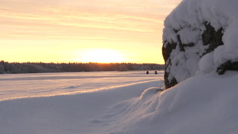 Beautiful-frozen-lake-at-sunrise-with-people-ice-fishing