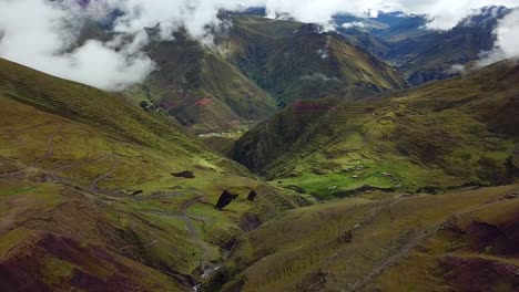 Aerial,-reverse,-drone-shot,-rising-over-green-hills,-roads,-fog-and-geographical-formations,-in-the-Andes-mountains,-on-a-overcast-day,-near-Cuzco,-in-Peru