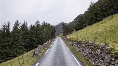 Hyperlapse-of-car-driving-over-small-road-on-the-side-of-a-steep-hill,-surrounded-by-pine-trees-and-rocks