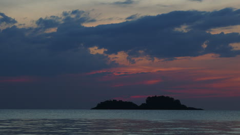 Timelapse-of-colorful-sky-with-slow-moving-clouds-and-calm-sea-with-small-islands-by-golden-hour