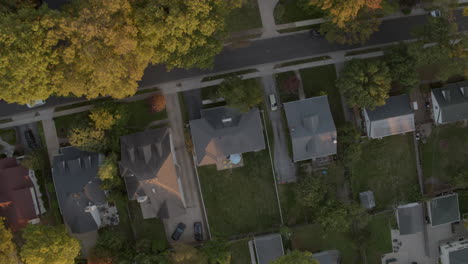 Straight-down-view-over-suburban-houses-and-street-with-white-car-driving-through
