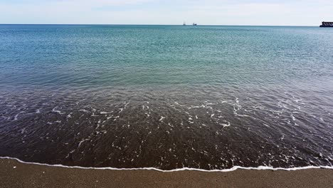 waves-gently-lap-the-sandy-beach-of-Malagueta-in-Malaga-on-a-sunny-day-in-the-Costa-del-Sol-in-Spain