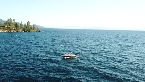 Luftbild-Auf-Motorboot-Im-Blauen-Wasser-Von-Grünen-Nadelbäumen-Küste-Von-Lake-Tahoe,-Grenze-Zu-Kalifornien,-Nevada,-USA