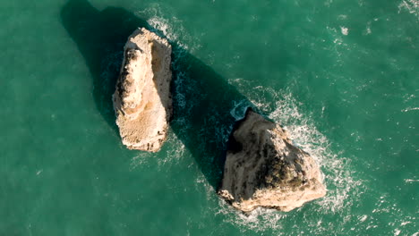 Antenne:-Felsen-Von-Oben-Mit-Blauem-Wasser,-Das-Sich-In-Der-Algarve,-Portugal,-Bewegt