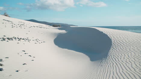 White-sand-dunes-with-black-pebbles-at-sea-in-Porto-Pino,-Sardinia,-bright-day