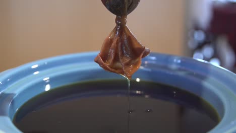 Cannabis-oil-draining-from-porous-bag-into-a-blue-pot