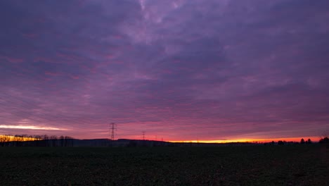Landscape-time-lapse-of-electricity-poles-during-a-cloudy-red-purple-sunset