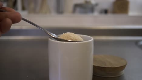 Slow-motion-shot-of-a-tablespoonful-of-sugar-taken-out-of-container-in-a-kitchen