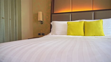 Close-up-bed-with-white-linen-and-cushions-in-hotel-room
