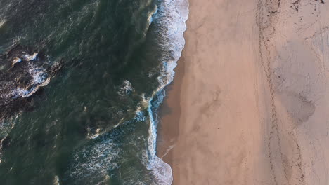 Vertikale-Luftaufnahme-Der-Küste-Mit-Wellen,-Die-In-Den-Sandstrand-Einbrechen