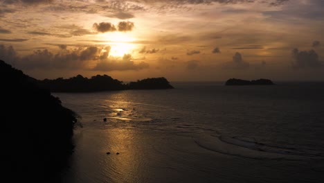 Atmospheric-golden-silhouette-orange-Panama-coastal-aerial-view-above-ocean-seascape-at-sunset