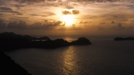 Panama-tropical-island-silhouette-golden-magic-hour-sunset-coastline-aerial-view-pull-back-along-coast
