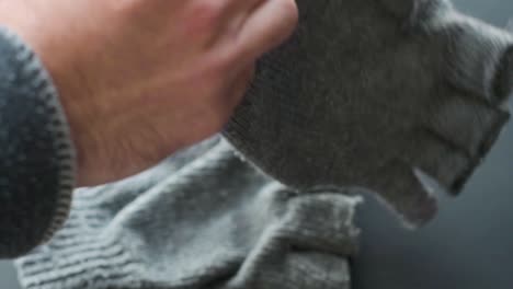 Detail-of-hands-putting-on-old-gray-winter-gloves-without-fingers