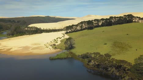 Aerial-tracking-shot-of-the-Giant-Sand-Dunes-and-green-fields-in-New-Zealand