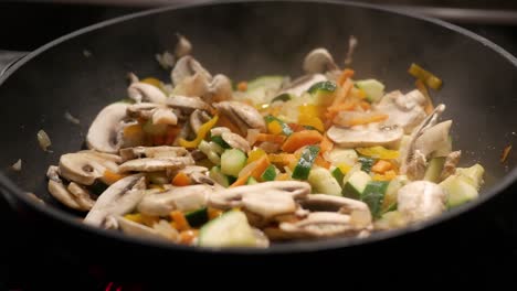 Close-up-pan-shot-of-finely-chopped-onions,-carrots,-mushrooms-and-other-vegetables-fried-in-oil-in-a-pan