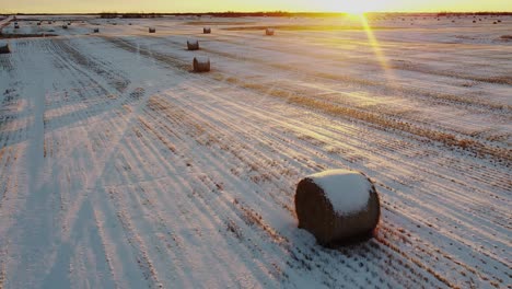 A-rising-drone-shot-of-some-snow-covered-bales-at-sunrise-facing-east