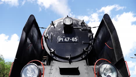 Low-point-of-view-time-lapse-over-forefront-antique-steam-train-locomotive-with-license-plate