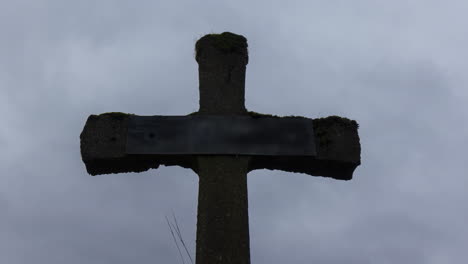 Time-lapse-of-grey-and-dark-clouds-passing-over-old-gravestone---slow-zoom-out