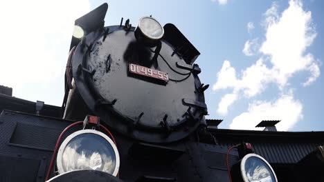 Historic-steam-locomotive-with-license-plate-and-lights-on-sunny-day-and-clouds-passing-by,-Time-Lapse