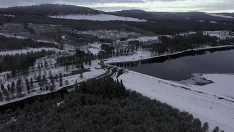 Filmische-Kreisförmige-Antenne-Des-Damms-Und-Der-Ruhigen-Winterlandschaft-Mit-Tiefen-Wäldern