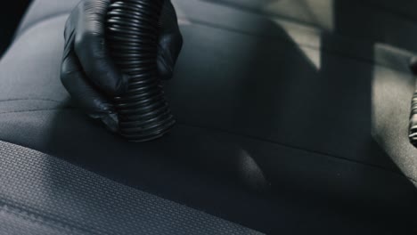Close-up-of-a-male-wearing-black-gloves-vacuum-an-black-interior-car