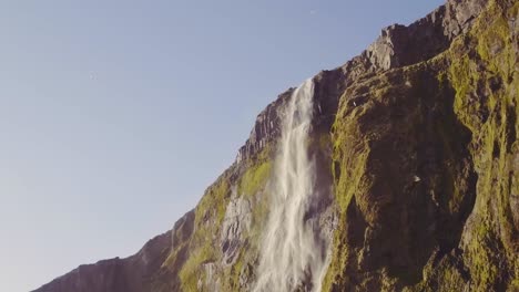 Iceland-waterfall-cascading-over-misty-cliff-with-birds-flying-past,-aerial-view