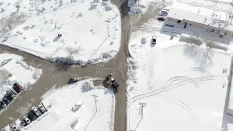 Birdseye-Aerial-View-of-Heavy-Machine-Vehicle-on-Asphalt-Road-in-Snowy-Winter-Countryside-American-Landscape