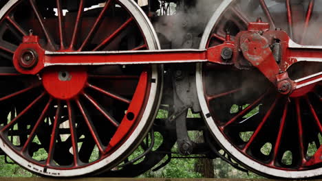 Close-shot-of-coal-powered-steam-train-steel-wheels-stoping-with-white-steam-smoke