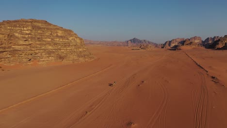 Riding-camels-through-desert-in-Wadi-Rum,-Jordan,-rising-aerial-view