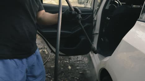 Male-cleaning-a-white-car-with-a-pressure-washer