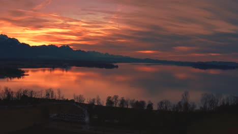 Anamorphe-4K-Luftdrohnenaufnahmen-Eines-Wunderschönen-Sonnenuntergangs-Mit-Roten-Wolken-Am-Malerischen-Bayerischen-Chiemsee-In-Süddeutschland-In-Der-Nähe-Der-Berge