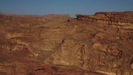Wadi-Rum-landscape-and-rock-formations-at-sunset,-aerial-flyover-reveal