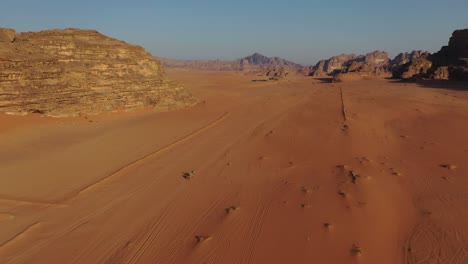 Person-riding-camels-through-desert-landscape-in-middle-east,-aerial-view