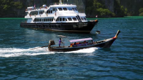Ein-Fischerboot,-Das-An-Einer-Riesigen-Fähre-Vorbeifährt,-Während-Es-An-Einem-Sonnigen-Tag-In-Thailand-Schnell-Den-Glitzernden-Blauen-Ozean-überquert---Weite-Aufnahme