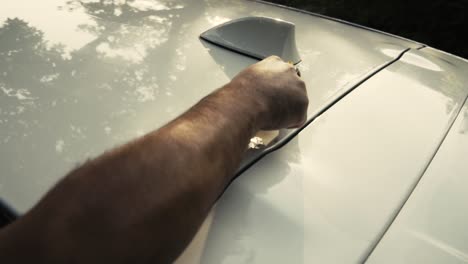 Close-up-of-a-male-wiping---drying-a-white-car