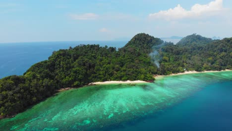 Eine-Luftaufnahme-Einer-Wunderschönen-Insel-Mit-Rauch-Aus-Dem-Dschungel