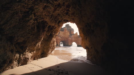 Beach-caves-in-the-Algarve,-Portugal-and-waves-gently-rolling-in-on-a-sunny-day