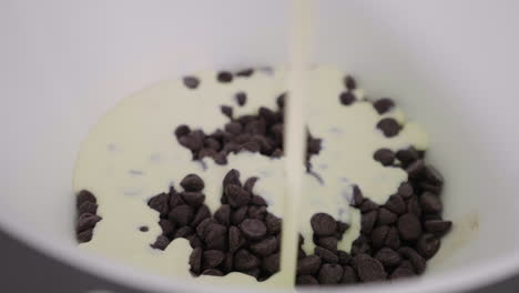 A-white-ceramic-bowl-of-chocolate-chips-has-cream-poured-all-over-it