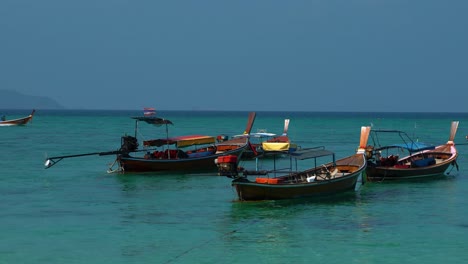 Traditional-and-iconic-longtail-boats-on-an-empty-sandy-beach-on-the-remote-island-Koh-Lipe-in-Thailand,-close-to-the-Malaysian-border