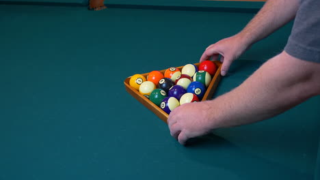 A-Caucasion-man-racking-a-set-of-billiard-balls,-for-a-game-of-eight-ball
