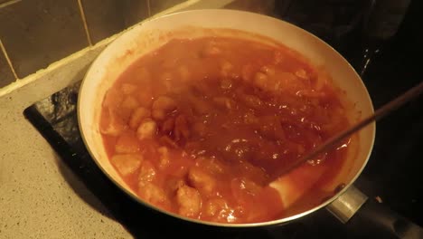 Timelapse-of-a-red-tomato-sauce-with-chicken-shimmering,-in-praparation-of-a-recipe