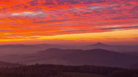 The-fiery-red-orange-sky-over-the-old-Ostrzyca-Proboszczowicka-volcano-during-sunset---time-lapse