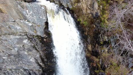 Aerial-tilt-down-viewpoint-of-rocky-splashing-waterfall-wilderness-close-up