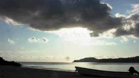Islas-Moheli-Comoras,-Lapso-De-Tiempo-De-Puesta-De-Sol-De-Playa-Con-Un-Barco-De-Silueta-En-La-Orilla