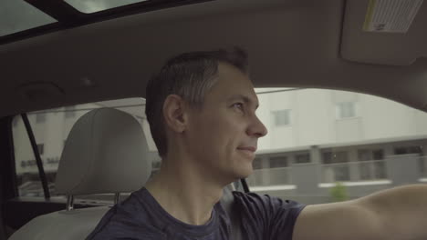 Man-driving-car-and-smiling-on-a-pretty-day,-dynamic-gimbal-movement