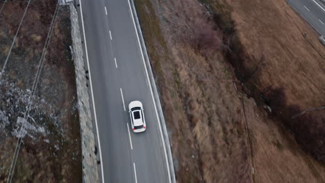 Aerial-Overview-of-White-Car-Driving-on-Empty-Mountain-Road