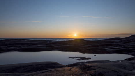 Time-lapse-shot-of-sunrise-above-a-rocky-coast-and-the-Skagerrak-ocean,-on-Justoya-island,-sunny-morning,-in-Aust-Agder,-Norway